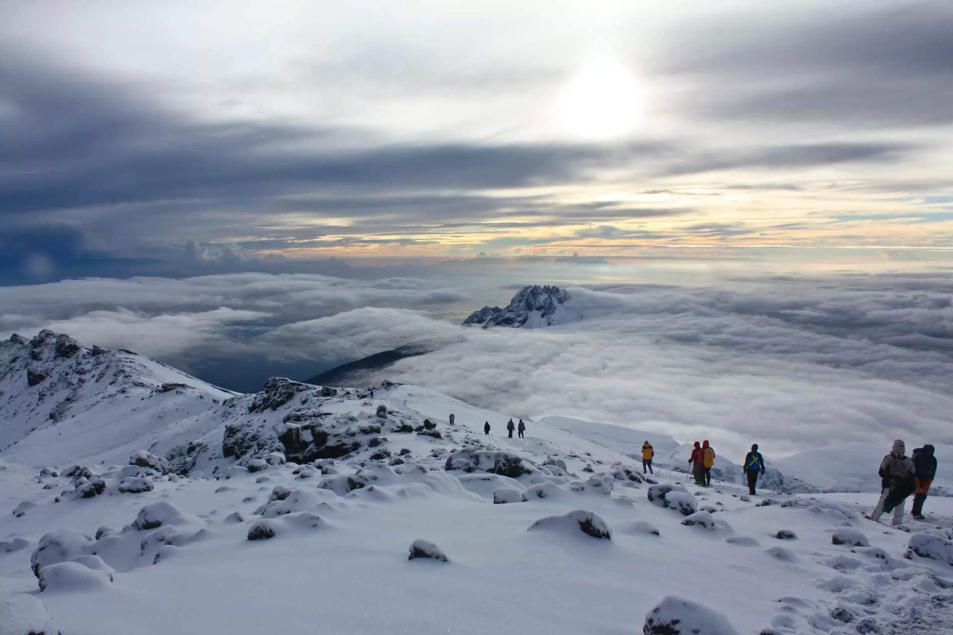 Climbers on Kilimanjaro trail with clouds and mountain views